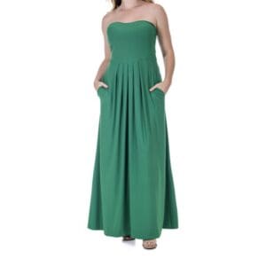 A woman wearing a strapless, floor-length green dress with pockets stands against a plain white background.