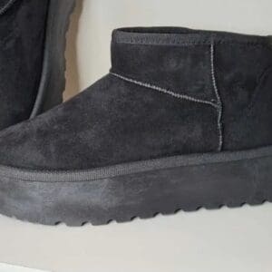 A single dark grey platform suede ankle boot with thick textured sole displayed on a shelf.