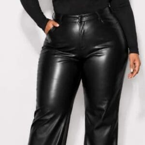 Person wearing a black long-sleeve top with a chest cutout and high-waisted black faux leather pants, standing against a plain background.