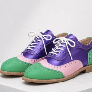 A pair of lace-up oxford shoes featuring a color-blocked design in purple, pink, and green.