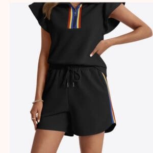 Black two-piece set consisting of a short-sleeved top with a zippered collar and matching shorts, both featuring rainbow-striped trim.