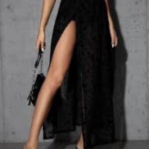 A black maxi skirt with a high side slit, worn with a crop top, black heels, and a small handbag.