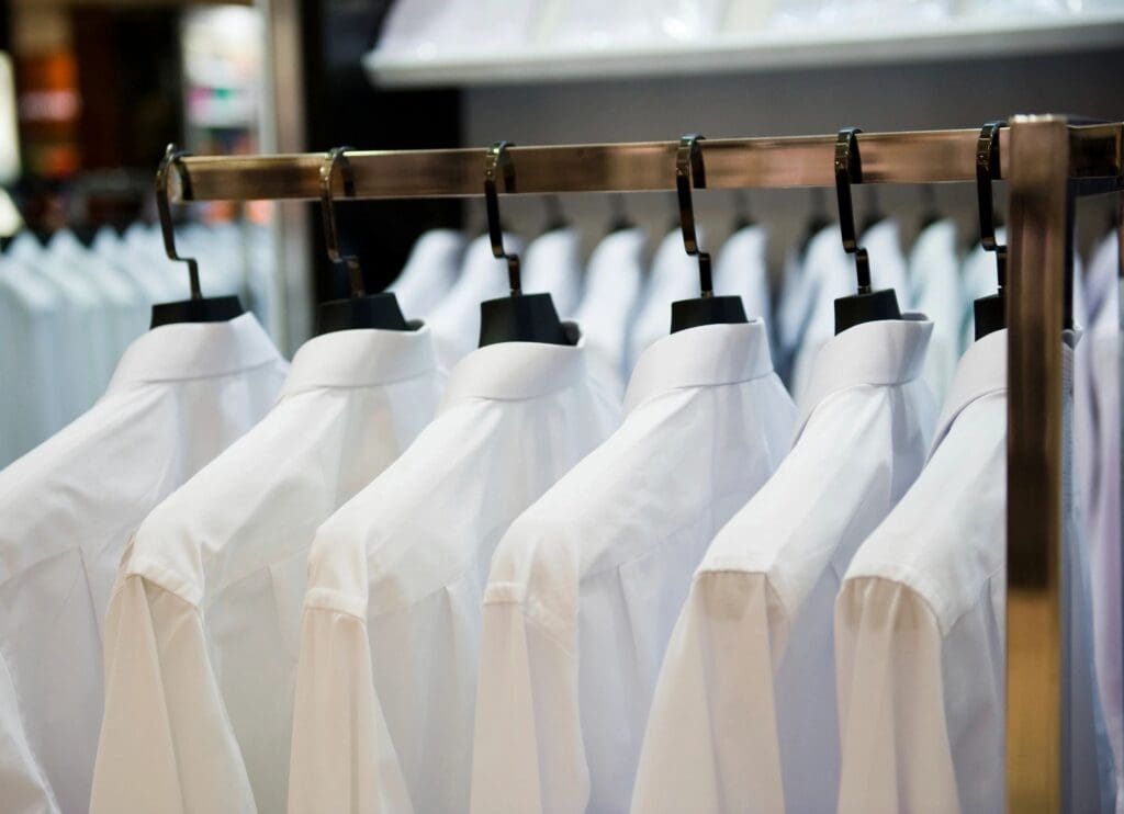 A rack of white button-down shirts on hangers.