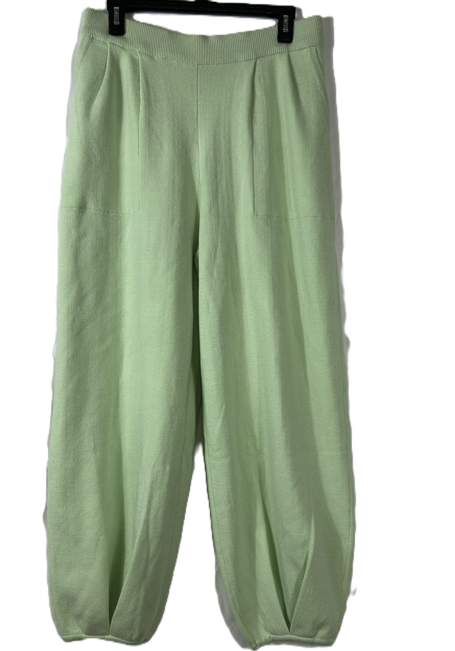 Light green, loose-fitting pants with pleats at the waist and ankle-length ballooned legs, displayed on a hanger against a white background.