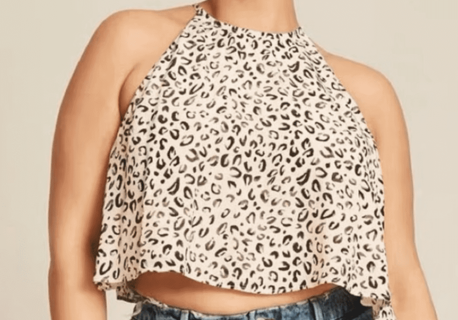 Person wearing a sleeveless, leopard print halter crop top and high-waisted, distressed blue jeans against a neutral background.