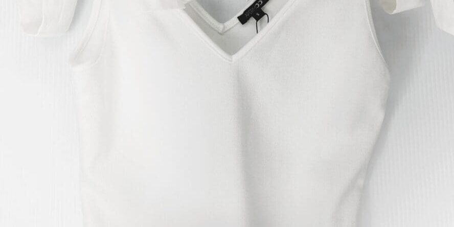 The White Tie Shoulder Top is a sleeveless V-neck with wide shoulder straps tied in bows, shown on a clear plastic hanger against a light background.