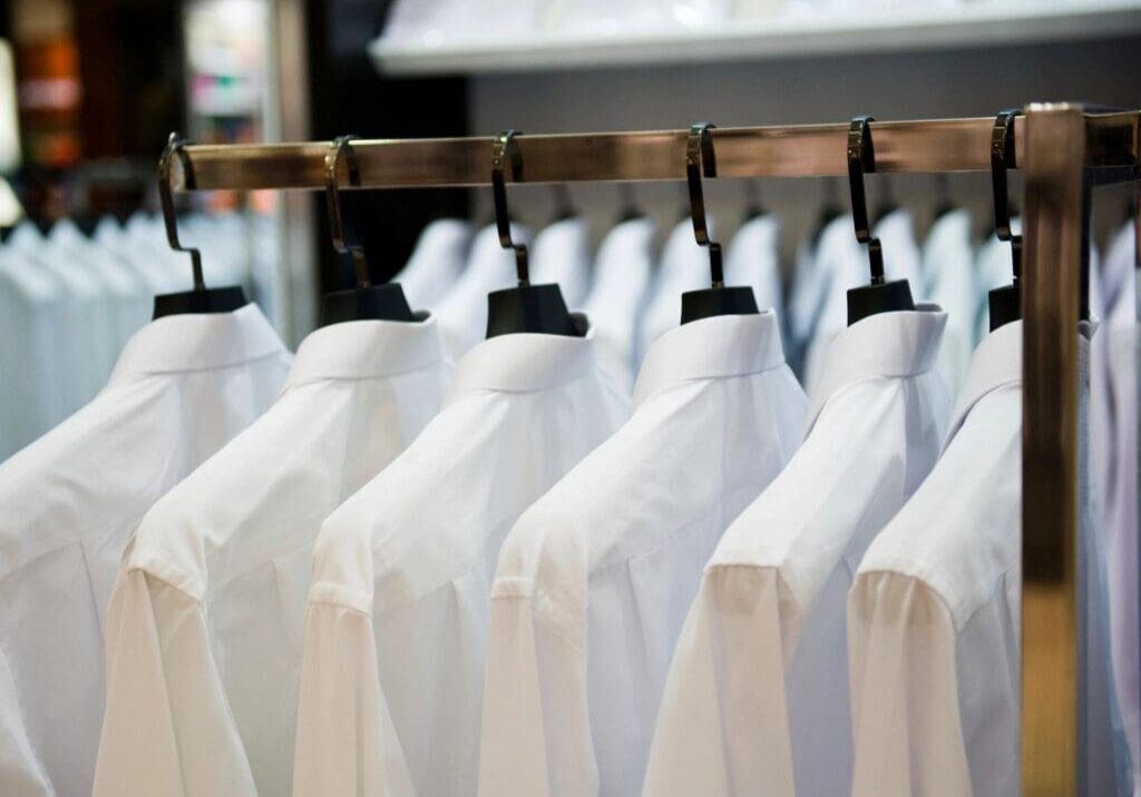 A rack of white button-down shirts on hangers.