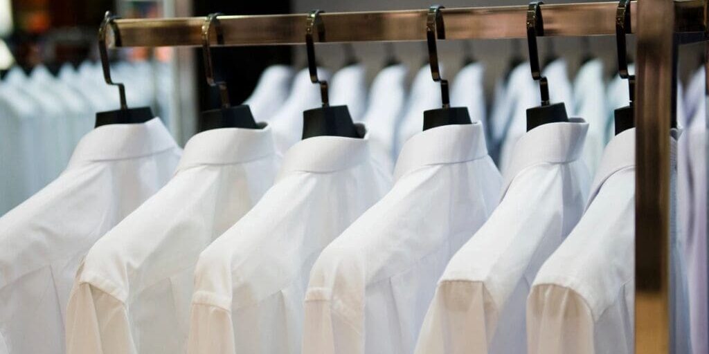 A rack of white button-down shirts on hangers.